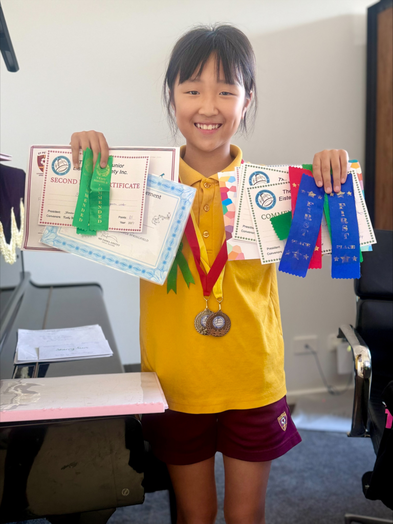 Speech and Drama student holding eisteddfod certificates and ribbon awards