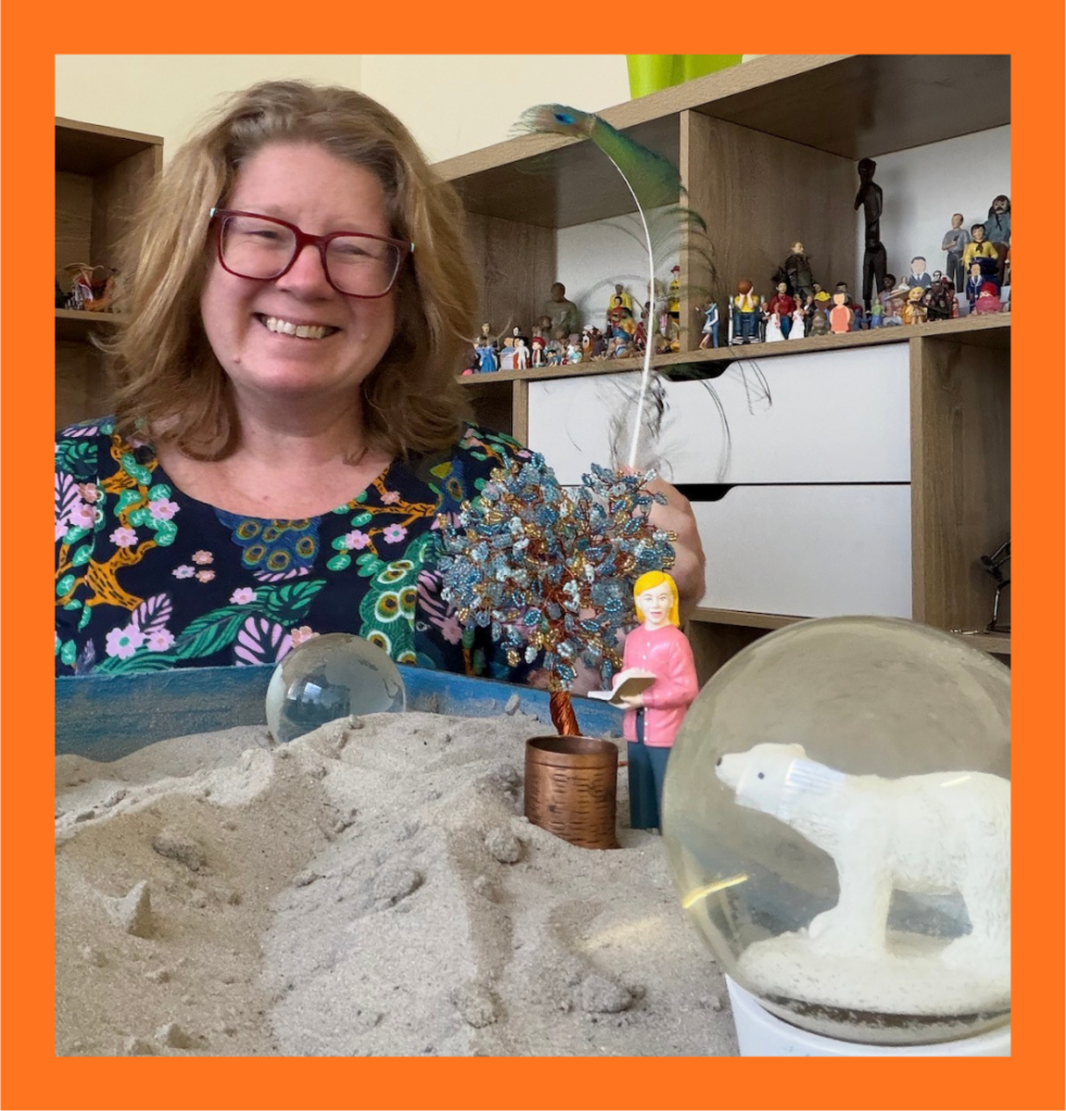 Yasmin, Flourish Ideas founder, with a sand tray therapy setup, framed in Flourish orange